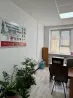 Жасыл өсімдіктермен, үстелмен және жарнамалық баннері бар аударма агенттігінің офистері.
