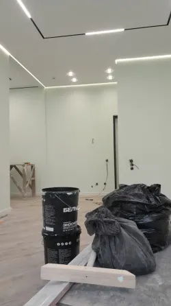 ремонт в комнате с черной и белой краской, рядом ведра и мешки с мусором