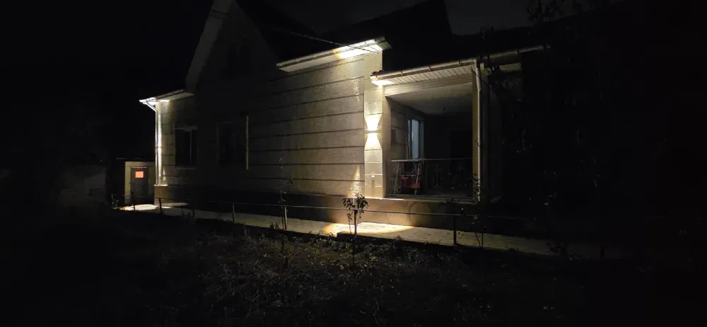 Жарықтандырылған террасасы бар ғимараттың түнгі көрінісі