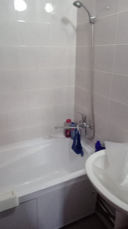 Диван, кілем және теледидармен жабдықталған бөлме, жарық терезе