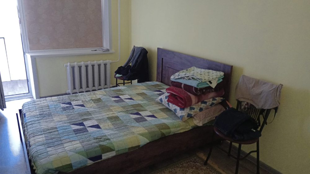 Жастықтармен жабдықталған төсегі бар жатын бөлме және орындықтар