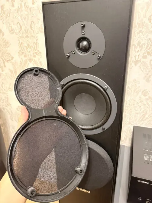 Человек держит решетку динамика напольной колонки Yamaha