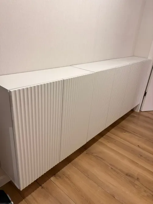 Ұзын ақ шкаф, рифленді есіктермен, ағаш еденде