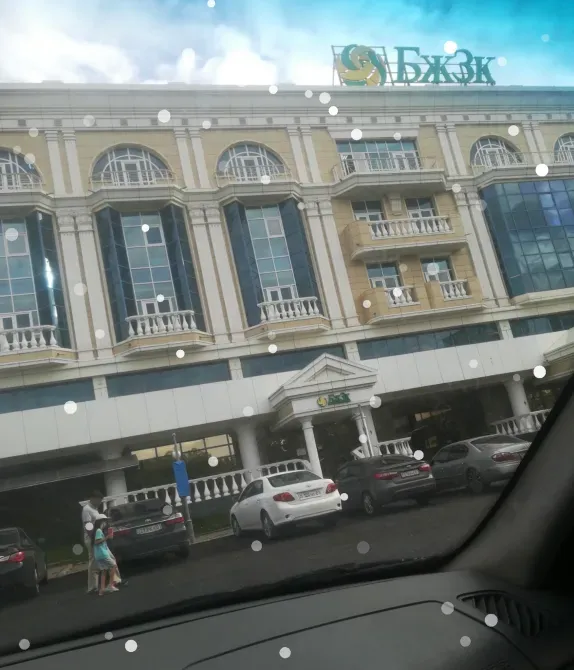 Фасад здания с вывеской и припаркованными автомобилями