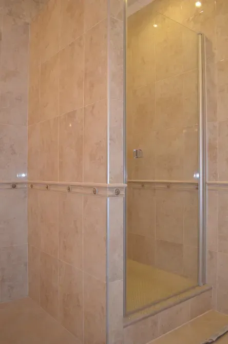 Уголок душевой кабины с прозрачной дверцей и плиткой