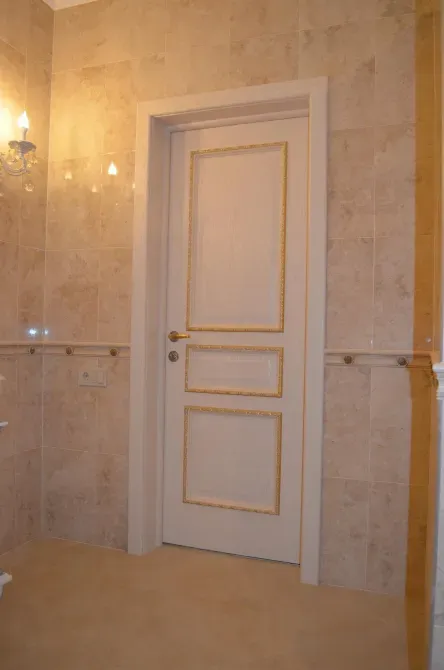 Дверь в ванную, выполненная в классическом стиле, с золотыми акцентами