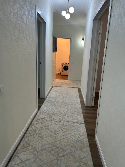 Длинный коридор с светлыми стенами, ковровым покрытием и двери, ведущие в комнаты