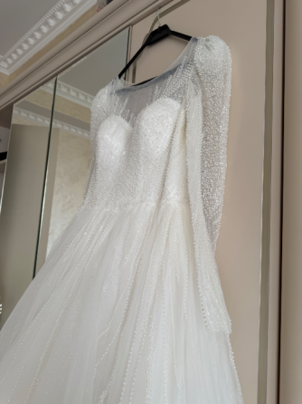 Пышное белое свадебное платье с жемчужными деталями и прозрачными рукавами