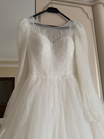 Пышное белое свадебное платье с жемчужными деталями и прозрачными рукавами