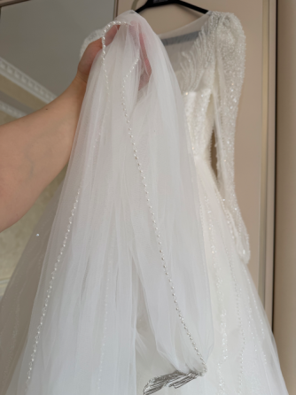 Пышное белое свадебное платье с жемчужными деталями и прозрачными рукавами