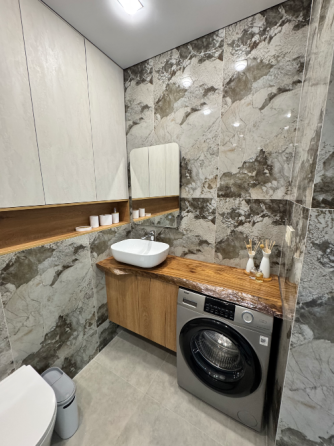 Заманауи жуыну бөлмесі, таспен әрленген, раковинасы мен жуғыш машинасы бар