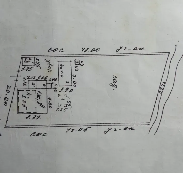 План участка с обозначением границ и размерами зданий. Изображение включает схему с различными измерениями и аннотациями для обозначения расположения объектов