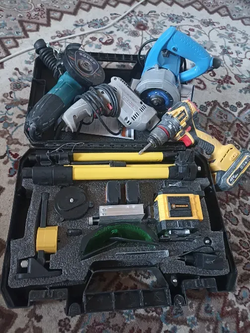 Электр құралдары бар құралдар жинағы, мысалы, бұрғы мен бұрғы, кілемнің фонында.