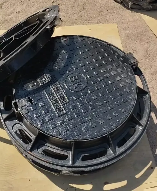 Открытая крышка черного люка с гладкой поверхностью и обозначением на внутренней стороне