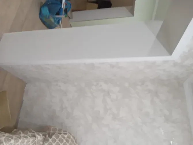 Белая стена в комнате с текстурой, сложенный диван и сумка на полу