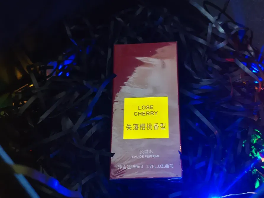 Упаковка парфюма Lose Cherry на фоне цветных огней