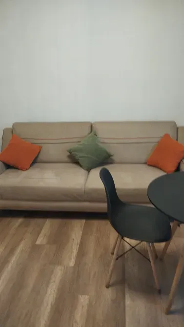 Диван с разноцветными подушками и стул на фоне небольшого столика