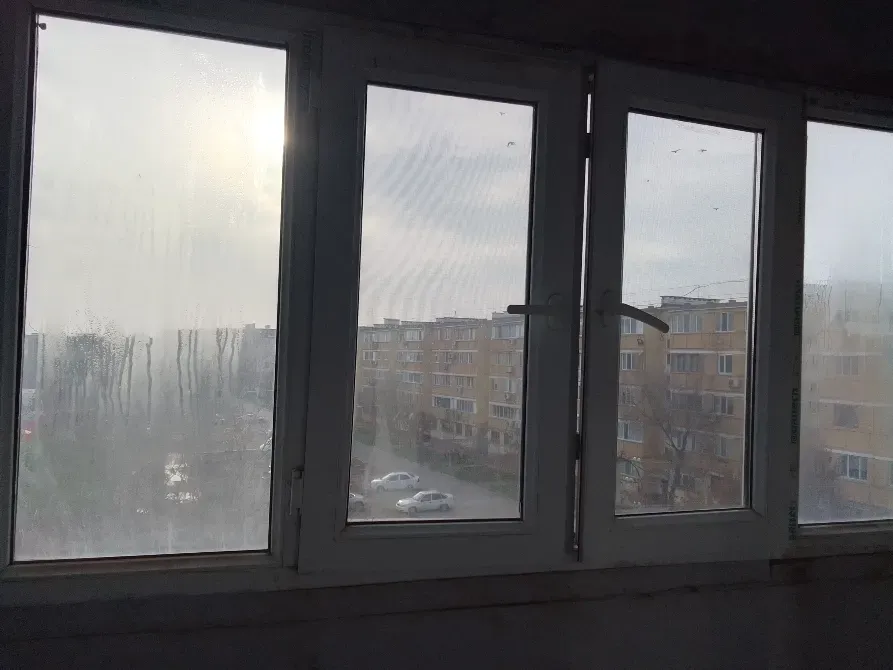 Вид из окна на многоэтажные дома и улицу с запотевшими стеклами