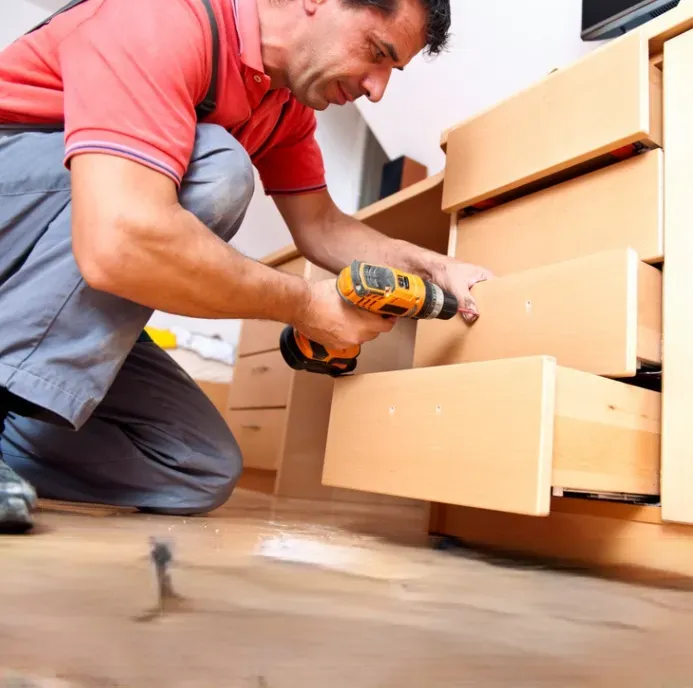 Мужчина устанавливает ящики в комод