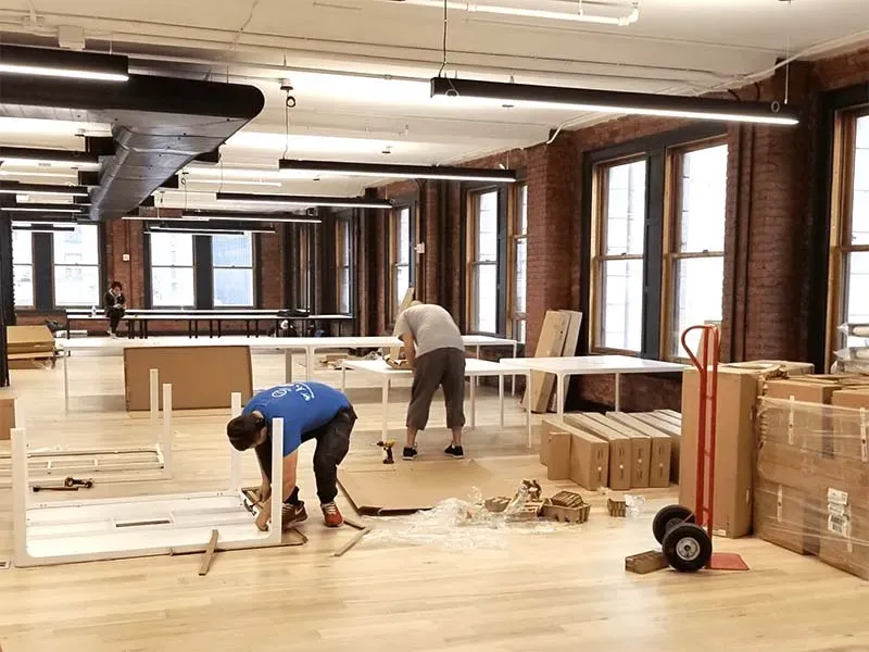 Рабочие собирают стол и другие предметы мебели