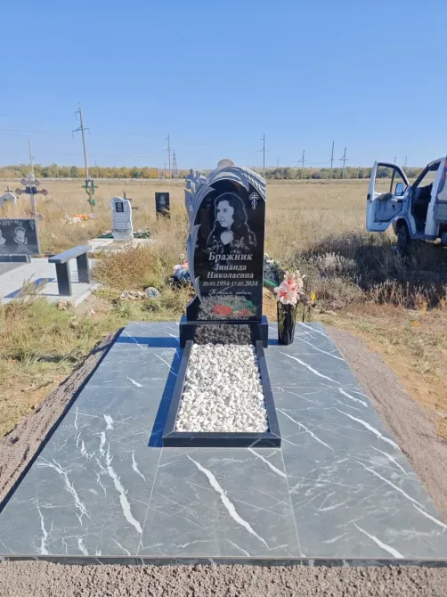 Надгробие с изображением и цветами на фоне открытого пространства