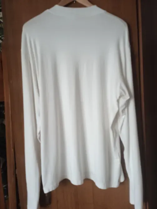 Задняя сторона белой рубашки на вешалке