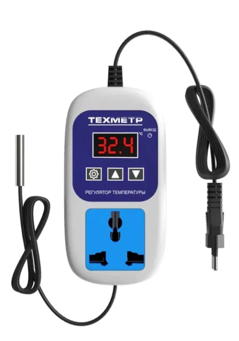 Фотография терморегулятора в бело-синем корпусе с отображением температуры и подключаемыми разъемами для электроприборов