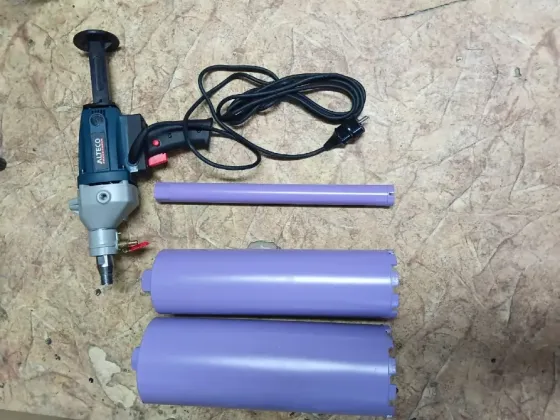 Электрический инструмент с насадками для работы с пластиковыми трубами, на фоне древесно-стружечной плиты