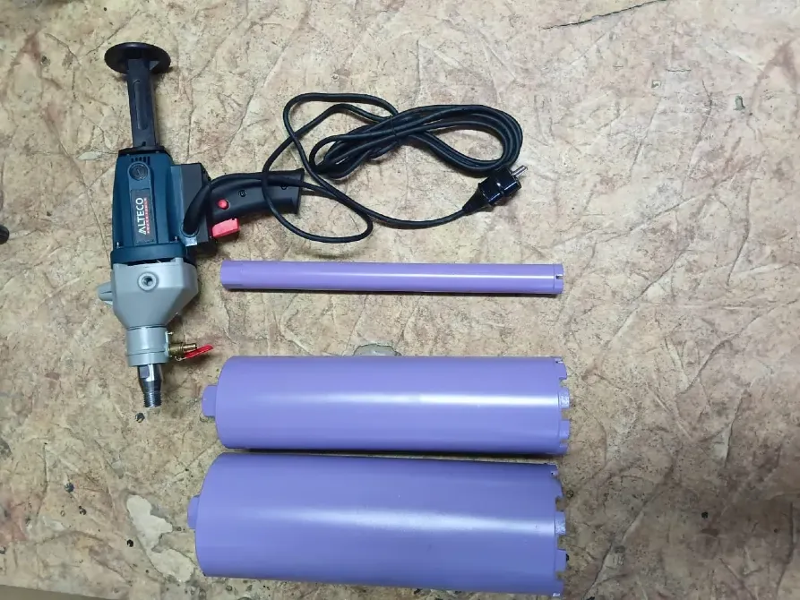 Электрический инструмент с насадками для работы с пластиковыми трубами, на фоне древесно-стружечной плиты