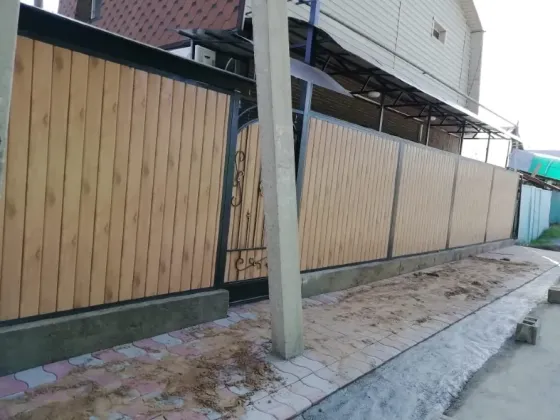 Забор из деревянных панелей с металлическими элементами и проемом для ворот