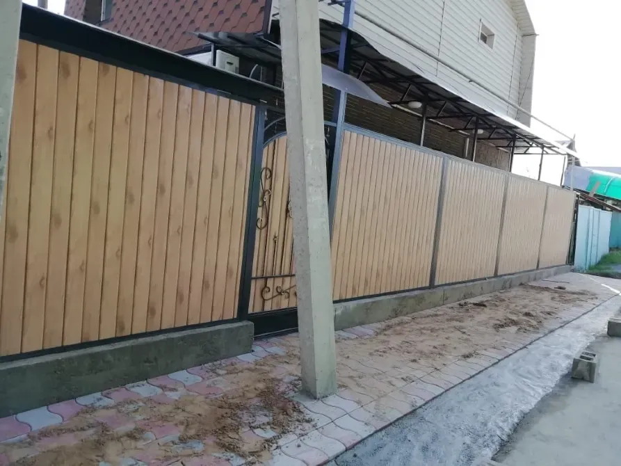 Забор из деревянных панелей с металлическими элементами и проемом для ворот