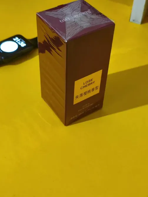 упаковка парфюма Lose Cherry на желтом столе