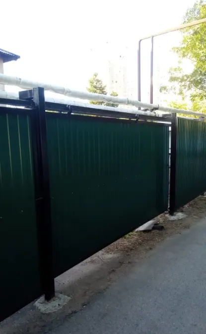 Зеленый металлический забор с трубами