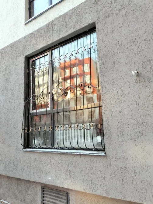 Окно с металлической решеткой на фасаде дома
