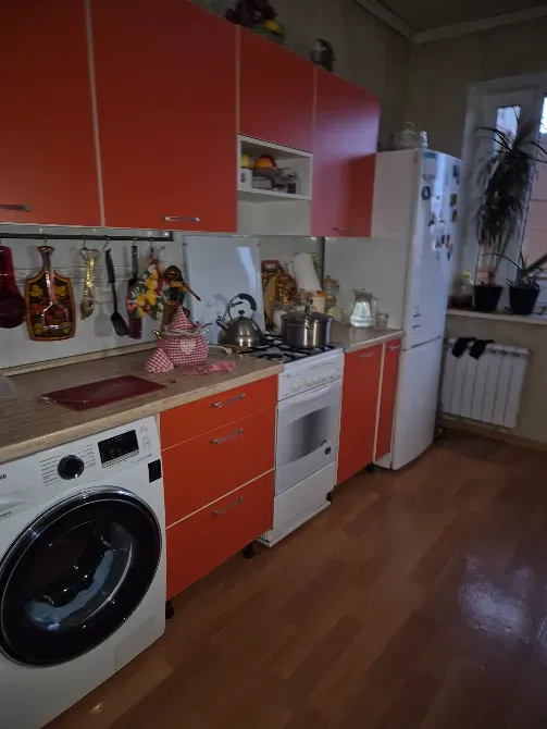 Современная кухня с оранжевыми гарнитурами и бытовой техникой