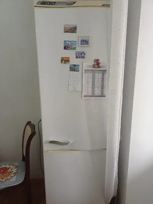 Холодильник на кухне с магнитами и заметками на дверце