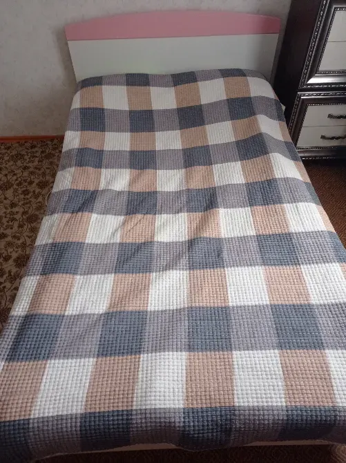 Вид кровати сверху с пледом в клетку и светлым изголовьем