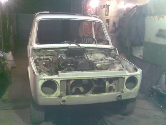 Старая машина без капота в неотремонтированном гараже