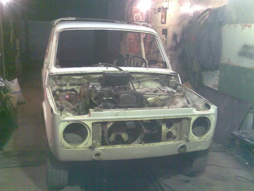 Старая машина без капота в неотремонтированном гараже