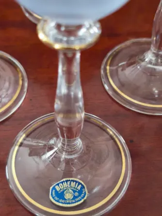 Стеклянные бокалы с золотымdecor и цветными узорами, выставленные на полке