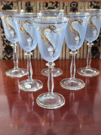 Стеклянные бокалы с золотымdecor и цветными узорами, выставленные на полке