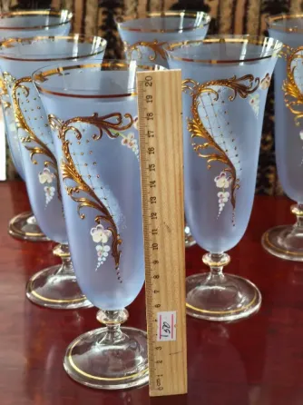 Стеклянные бокалы с золотымdecor и цветными узорами, выставленные на полке