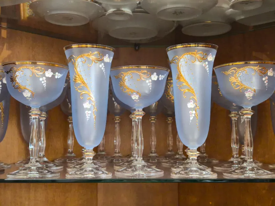 Стеклянные бокалы с золотымdecor и цветными узорами, выставленные на полке