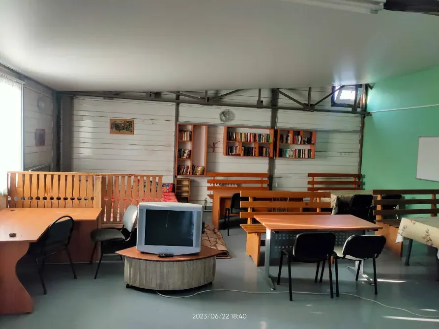 Интерьер комнаты для отдыха с книгами, телевизором и столами для работы