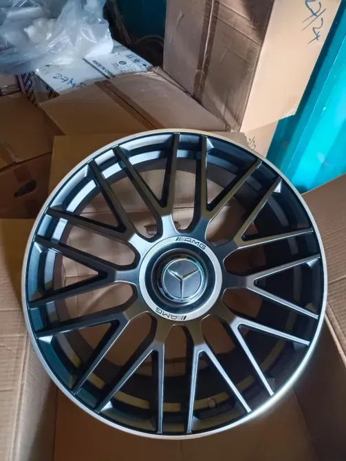 Автомобильное колесо с логотипом Mercedes-Benz, черный и серебристый цвета, на фоне коробок