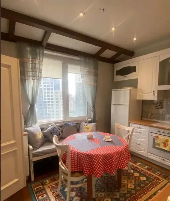 Кухня с обеденной зоной, столом в красной скатерти и окнами