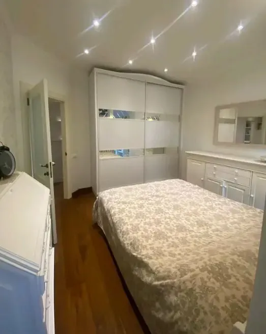Спальня с двуспальной кроватью, зеркалом и белыми шкафами