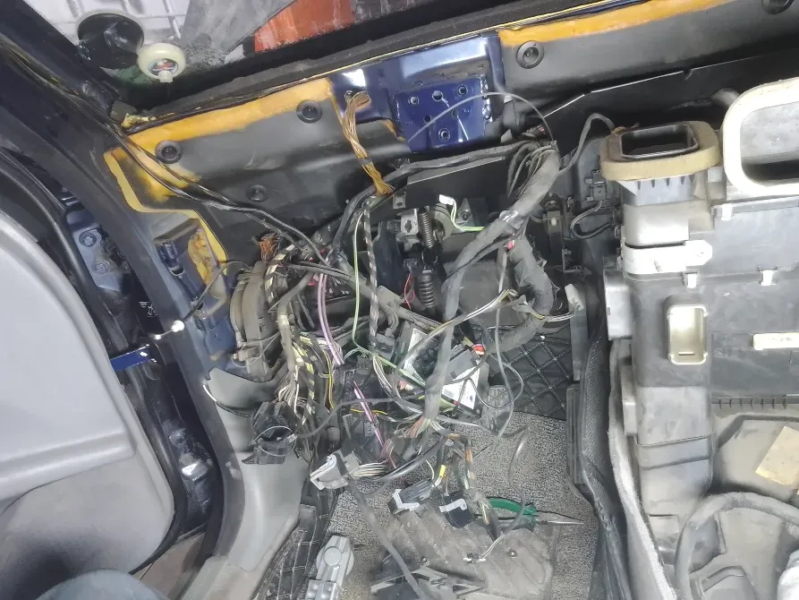 Сильно запутанные провода и электрические соединения под капотом автомобиля