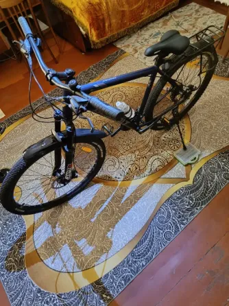 Велосипед на ковре с узором в интерьере комнаты