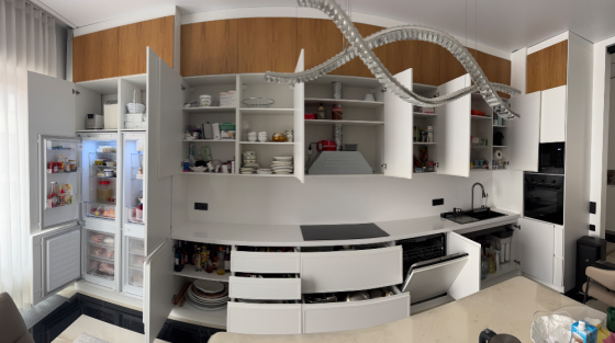 Современная кухня с белыми и деревянными шкафами, встроенной техникой и черной столешницей